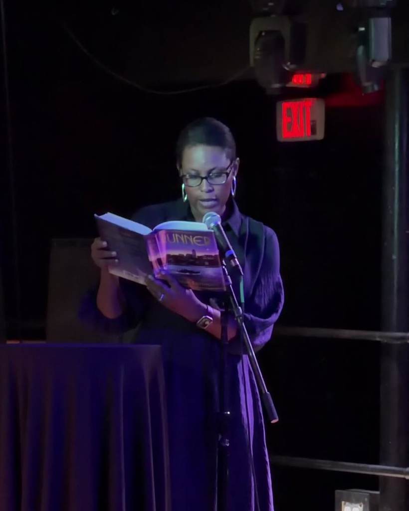An author reading on stage at The Cardigan Connection in Providence