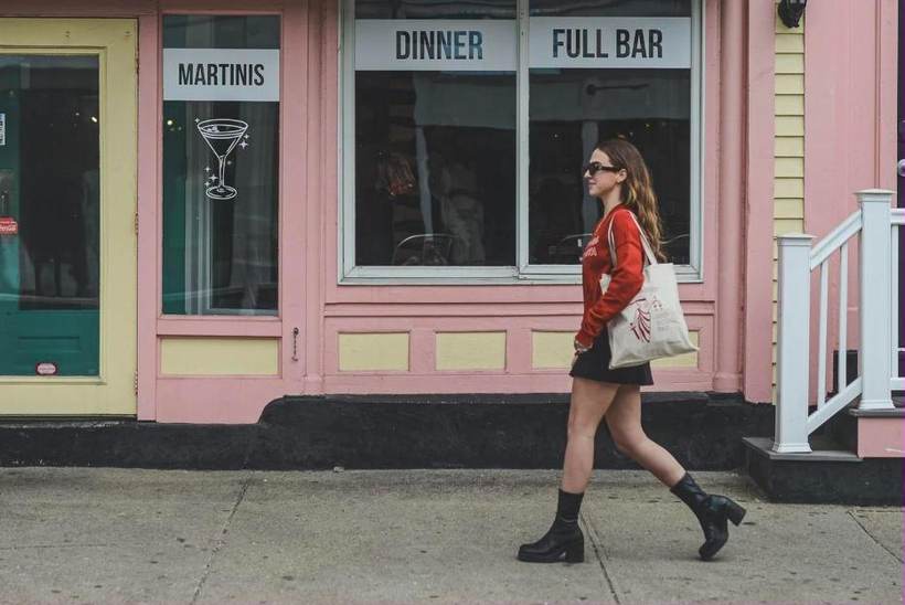 Brand photography of a woman walking past a pink storefront in Newport, Rhode Island